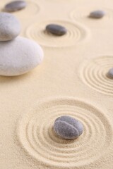 Fototapeta na wymiar Zen garden stones on sand with pattern, closeup