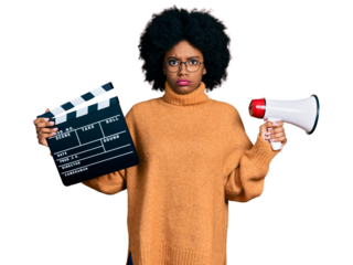 Young african american woman holding video film clapboard and megaphone skeptic and nervous, frowning upset because of problem. negative person.