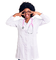 Young african american woman wearing doctor coat and stethoscope doing peace symbol with fingers over face, smiling cheerful showing victory