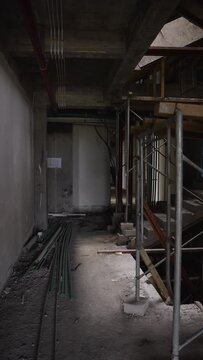 Interior of an unfinished construction site with exposed piping and scaffolding. Building under construction process overview, walking inside. Vertical orientation.