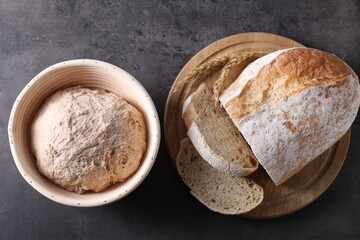 Fresh sourdough in proofing basket and bread on grey table, top view