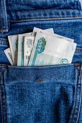 Russian thousand-ruble banknotes stick out from the waistband of blue jeans