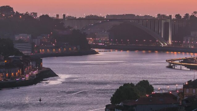 Day to night transition aerial view of the historic city of Porto, Portugal panoramic timelapse from the Dom Luiz bridge. Illuminated waterfront and curved river from above