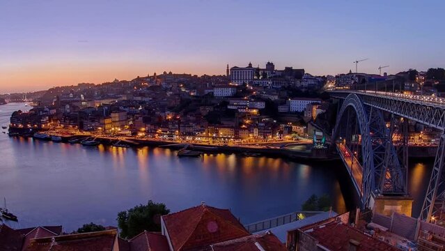 Panorama old city Porto at river Duoro, with Port transporting boats after sunset timelapse with the Arrabida bridge day to night transition, Oporto, Portugal