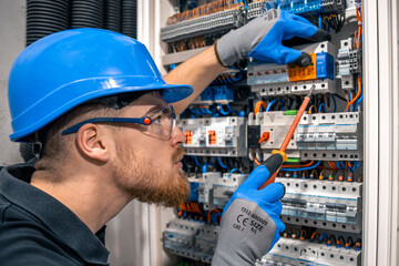 Male electrician working in a switchboard with fuses. - 775077955