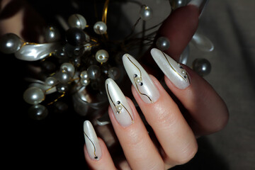 Pearl design with rhinestones on long extended nails.