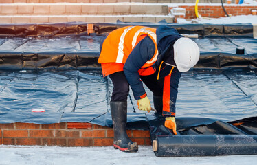 Waterproof installation at new house construction. Builders installing underfloor waterproof...