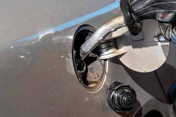 A man filling fuel tank of his car with diesel fuel at the gas station close up, as cost of fuel going up - obrazy, fototapety, plakaty