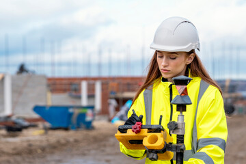 Female site engineer surveyor working with theodolite total station EDM equipment on a building...