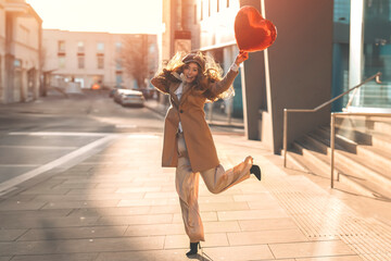 young happy woman with a heart-shaped balloon falling a love, having a fun day, walking around...