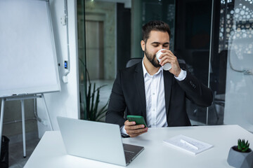 businessman sitting in in office working with laptop computer and mobile drink coffee - 775084308
