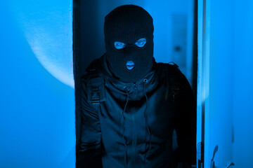 Mysterious figure of man in blue-lit apartment corridor