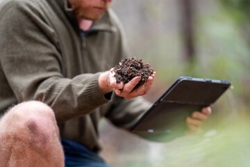 farmer collecting soil samples in a test tube in a field. Agronomist checking soil carbon and plant...