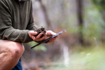 farmer collecting soil samples in a test tube in a field. Agronomist checking soil carbon and plant health on a farm