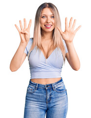 Obraz na płótnie Canvas Young beautiful blonde woman wearing casual clothes showing and pointing up with fingers number nine while smiling confident and happy.