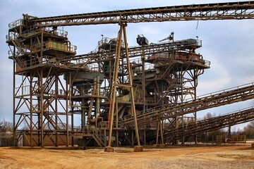 Grungy shot of gravel quarry, with rusty metal frames and and conveyor belts - 775087568