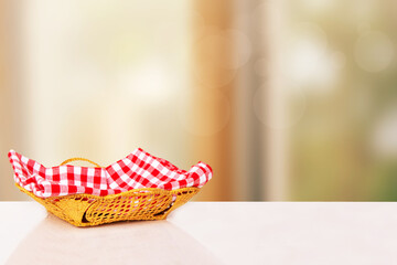 Empty picnic basket. Close-up of a empty straw basket with a checkered red napkin on table over...