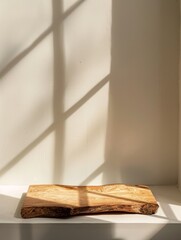 A wooden cutting board is softly illuminated by window light, showcasing a blend of shadows and textures in a homely kitchen scene.
