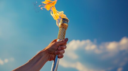 arm holding the Olympic torch with blue sky background in high resolution