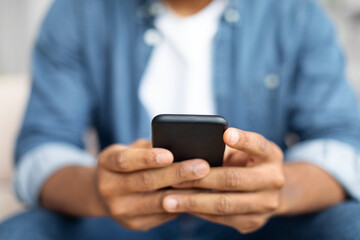 Black Man Sitting on Couch Using Cell Phone