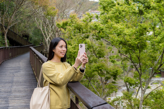 Tourist woman use mobile phone to take photo in the walking trail in the forest