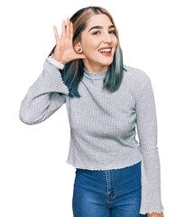 Fototapeta premium Young modern girl wearing casual sweater smiling with hand over ear listening an hearing to rumor or gossip. deafness concept.