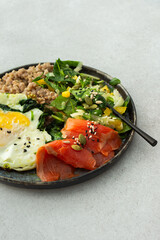 Buckwheat with fried egg and salmon fish, mix salad with fresh herbs and peppers