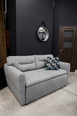 Gray soft sofa in the interior against a gray wall