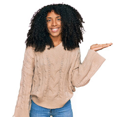 Young african american girl wearing casual clothes smiling cheerful presenting and pointing with...