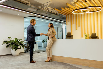 Warm Handshake Between Colleagues In Modern Office Lobby Under Ambient Lighting