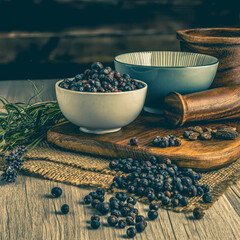 Juniper Berries on wooden table background. Herbs, spices and dried food baking ingredient. Mortar...