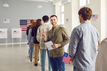 Happy american voter making victory gesture while registering at polling station on election day....
