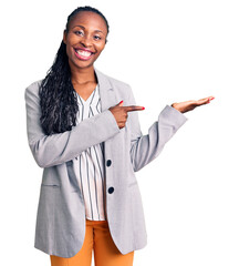 Young african american woman wearing business clothes amazed and smiling to the camera while presenting with hand and pointing with finger. - obrazy, fototapety, plakaty