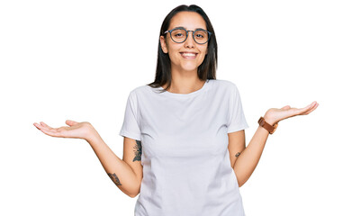 Young hispanic woman wearing casual white t shirt smiling showing both hands open palms, presenting and advertising comparison and balance