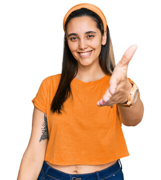 Young hispanic woman wearing casual clothes smiling friendly offering handshake as greeting and welcoming. successful business.