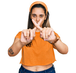 Young hispanic woman wearing casual clothes rejection expression crossing fingers doing negative...