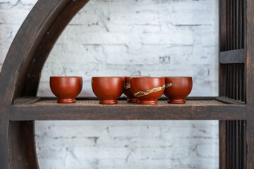 Set of clay crockery or ceramic kitchenware which are kept on the wooden shelf. Interior decoration object photo.