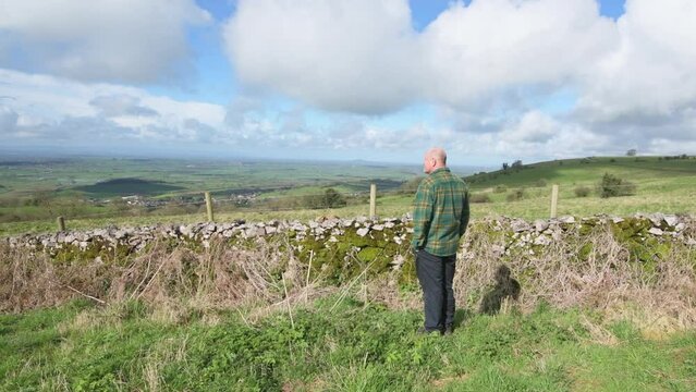 Retired man enjoying the view from Deerleap viewpoint whilst walking in the Mendip Hills.