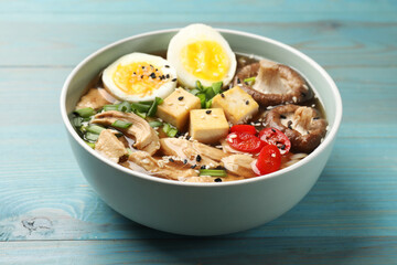 Bowl of delicious ramen on light blue wooden table. Noodle soup