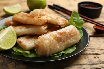 Tasty fried spring rolls served on wooden table, closeup