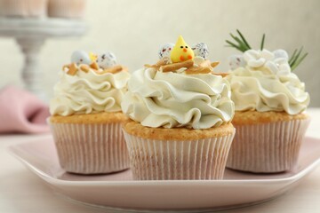 Tasty Easter cupcakes with vanilla cream on light table