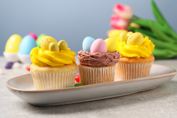 Tasty decorated Easter cupcakes on grey table, closeup