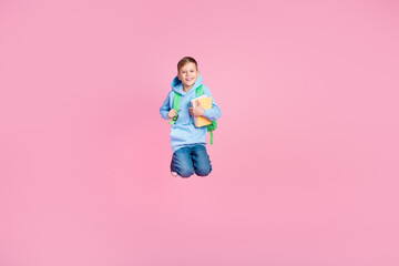 Full size portrait of cheerful excited schoolkid hold rucksack book jump empty space isolated on pink color background