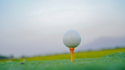 Close-up golf ball on tee with blur green bokeh background.