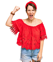 Young brunette woman with short hair wearing casual summer clothes and diadem angry and mad raising fist frustrated and furious while shouting with anger. rage and aggressive concept.