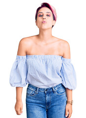 Young beautiful woman with pink hair wearing casual clothes looking at the camera blowing a kiss on air being lovely and sexy. love expression.