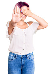 Young beautiful woman with pink hair wearing casual clothes and glasses covering eyes with hands and doing stop gesture with sad and fear expression. embarrassed and negative concept.