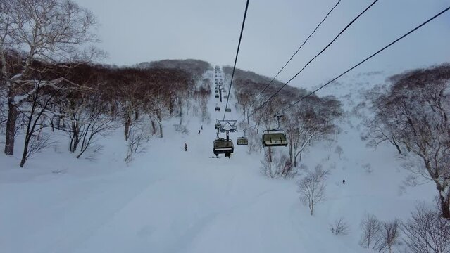 Niseko, Japan: Skiers and snowboarder riding the powder snow under a chairlift in the famous Niseko ski resort in Hokkaido in winter in northern Japan