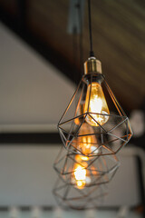 Classic style lightbulb ceiling lamp with iron cage glowing in orange light shade. Interior decoration object photo, selective focus.