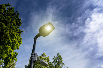 Modern street lamp in park against background of dramatic evening sky. Lamppost view from below